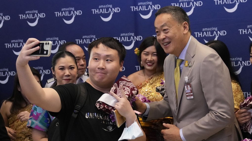 Chinese tourists takes selfies with Thailand's Prime Minister Srettha Thavisin, right, on their arrivals at Suvarnabhumi International Airport in Samut Prakarn province, Thailand, Monday, Sept. 25, 2023. (AP Photo/Sakchai Lalit, File)