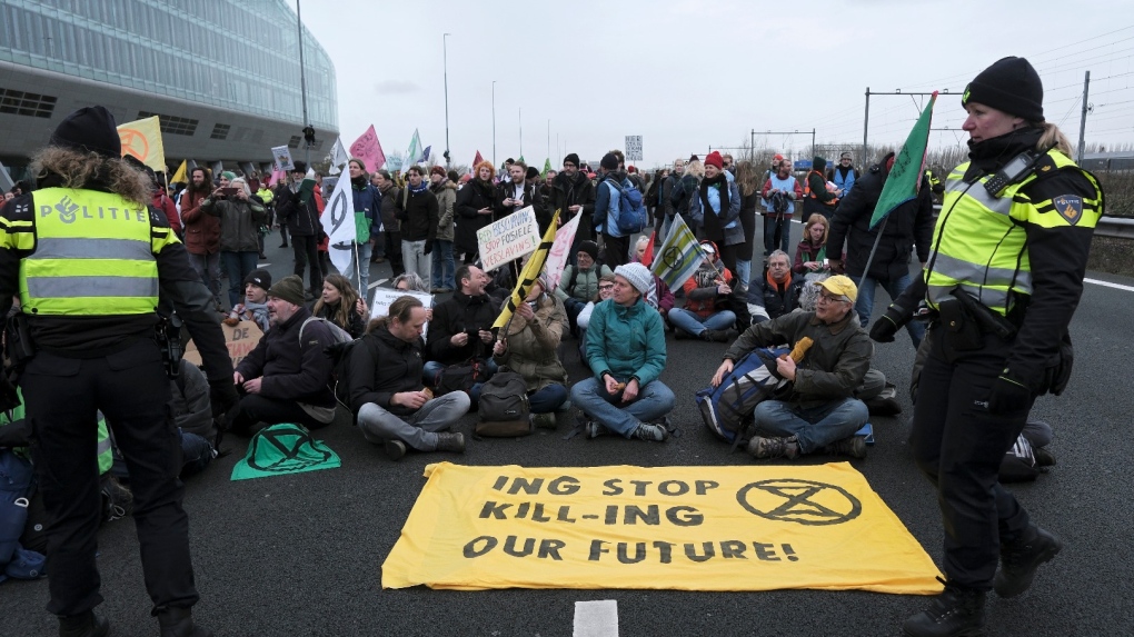 Police officers speak with climate activists block the main highway around Amsterdam near the former headquarters of a ING bank to protest its financing of fossil fuels, Saturday, Dec. 30, 2023. Protesters walked onto the road at midday, snarling traffic around the Dutch capital in the latest road blockade organized by the Dutch branch of Extinction Rebellion. (AP Photo/Patrick Post)
