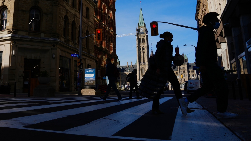 The Canadian flag flies on the Peace Tower of Parliament Hill as pedestrians make their way along Sparks Street Mall in Ottawa on Tuesday, Nov. 9, 2021. THE CANADIAN PRESS/Sean Kilpatrick
