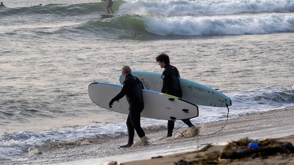 Surfers head out in the early morning to catch the waves in Malibu Beach, Calif. on Friday, Dec. 29, 2023. Powerful surf rolled onto beaches on the West Coast and Hawaii as a big swell generated by the stormy Pacific Ocean pushed toward shorelines, causing localized flooding. (AP Photo/Richard Vogel)
