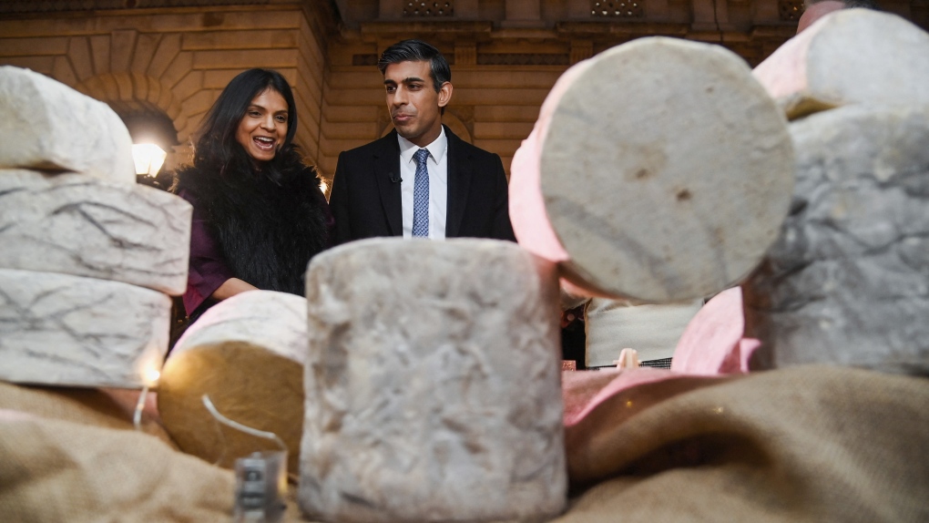 Britain's Prime Minister Rishi Sunak and his wife, Akshata Murty, look at cheeses as they visit a food and drinks market promoting British small businesses over the festive season in Downing Street in London, Wednesday, Nov. 30, 2022. (Toby Melville/Pool via AP)